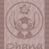 Beige knit and purl blanket with a textured Stitch character motif inside a circle and “ohana” lettering, framed by a garter stitch border on a light background