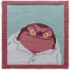 Hand-knitted Jumba Jookiba character square panel with a brown garter stitch border on a light teal background. The design features Jumba from Disney’s Lilo & Stitch with glowing yellow eyes, a mischievous grin, and a white lab coat. Colorwork knitting design created using white, light teal, beige, brown, and yellow shades.