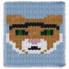 Kentucky Wildcat chunky knit blanket pattern featuring a close-up portrait of a wildcat mascot face with camel fur, dark eyes with green pupils, pink nose and white muzzle markings, set against a sky blue background, knitted in jumbo yarn using finger knitting colorwork technique.