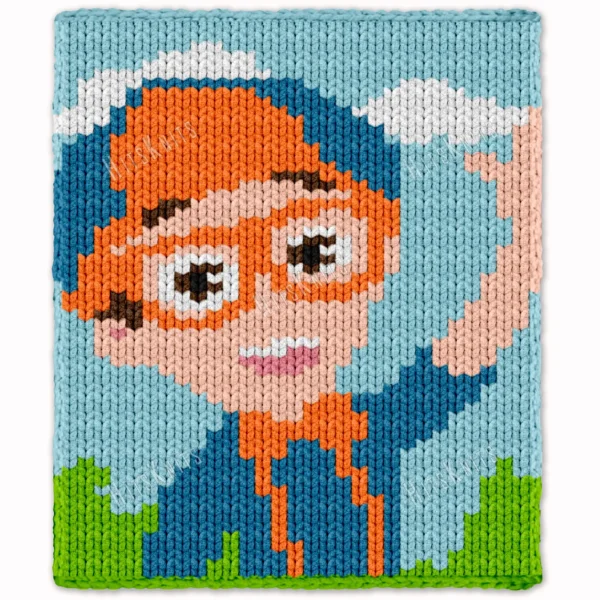 Pixel-style chunky knit blanket inspired by Blippi, featuring a cheerful character with bright orange glasses, orange hat, blue outfit, and smiling expression on a sky-blue background with white clouds and green grass.
