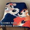 Chunky knitted blanket featuring Lady and the Tramp in a close-up face-to-face pose on a navy blue background. The design shows the two classic cartoon dogs with expressive eyes, floppy ears, soft beige and brown fur, and playful smiles in colorful pixel-style stitches. Cozy romantic graphghan blanket