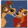 Chunky knitted blanket featuring Lady and the Tramp in a close-up face-to-face pose on a navy blue background. The design shows the two classic cartoon dogs with expressive eyes, floppy ears, soft beige and brown fur, and playful smiles in colorful pixel-style stitches. Cozy romantic graphghan blanket