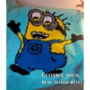 A playful corner-to-corner crochet blanket featuring a cheerful Minion character with raised arms, dressed in bright blue overalls with black gloves and shoes. The design is worked on a soft mint green background, making the bold yellow, blue, black, white, and gray details stand out beautifully.