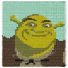 Chunky knit Shrek face blanket in jumbo chenille yarn, cartoon graphghan throw pattern with green ogre portrait and colorful background.