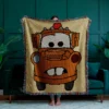 Large C2C crochet blanket featuring Tow Mater from Disney Pixar Cars in pixel art style, with a beige background and colorful fringe border, displayed in a modern living room.