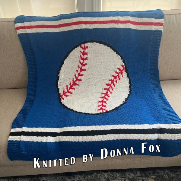 Baseball Intarsia Knit Blanket Pattern - a white baseball with red stitching and a black outline centered on a blue background with a garter stitch border, worked in stockinette intarsia colorwork with 4 colors: Blue, White, Red, Black.