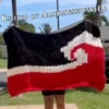Maori Flag Blanket Finger Knitting Pattern - black, red and white Tino Rangatiratanga Maori sovereignty flag with a central white koru, bold high-contrast mood, worked in stockinette colorwork intarsia with 3 colors: Black, Red, and White.