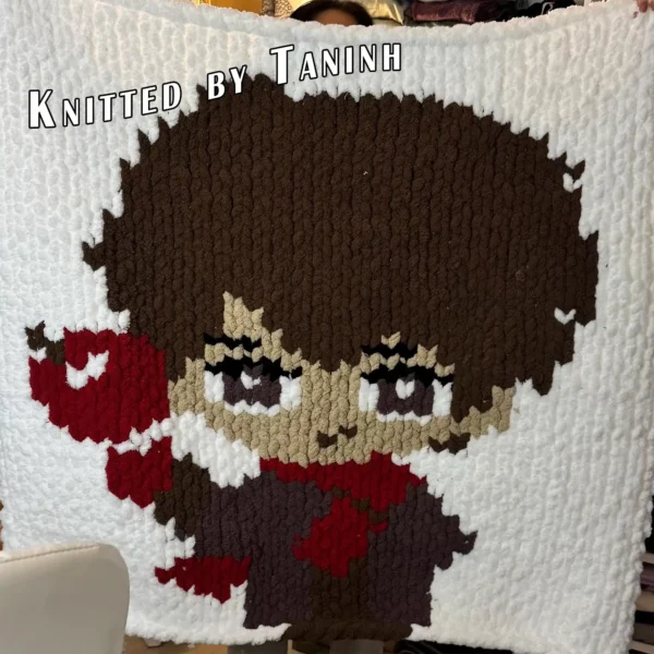 Caleb Finger Knit Blanket Pattern - video game character with dark brown hair holding a red apple, purple outfit and red accents on a white background, worked in stockinette colorwork intarsia with 6 colors: White, Brown, Purple, Red, Powder, Black.