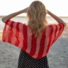 Easy striped lace bolero knitting pattern showing a loose summer shrug worked in thin cotton yarn with lace eyelet rows at each colour change, in coral and red stripes, one size fits most.
