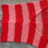 Easy striped lace bolero knitting pattern showing a loose summer shrug worked in thin cotton yarn with lace eyelet rows at each colour change, in coral and red stripes, one size fits most.