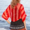 Easy striped lace bolero knitting pattern showing a loose summer shrug worked in thin cotton yarn with lace eyelet rows at each colour change, in coral and red stripes, one size fits most.