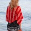 Easy striped lace bolero knitting pattern showing a loose summer shrug worked in thin cotton yarn with lace eyelet rows at each colour change, in coral and red stripes, one size fits most.