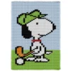Snoopy Golfing Finger Knit Blanket Pattern showing a white beagle in a lime green golf visor and red collar mid-swing with a golf club and orange club head, on lime green grass against a sky blue background, worked in stockinette colorwork with 6 colors: Sky, Lime, White, Black, Orange, and Red.