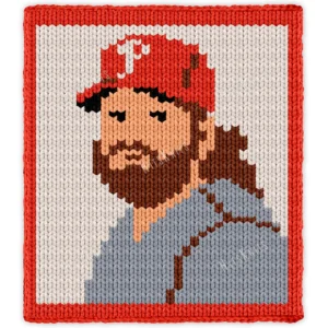 John Kruk Chunky Blanket Knitting Pattern showing a caricature portrait of baseball player John Kruk in a red cap and gray uniform with a brown beard, on an ivory background with a red border, worked in stockinette colorwork intarsia with 6 colors: Ivory, Red, Gray, Brown, Powder, and Black.