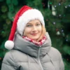 Santa Hat Knitting Pattern showing a long red knitted Santa hat with a soft fluffy white brim and a white pompom, an easy knit and purl Christmas hat for adults.