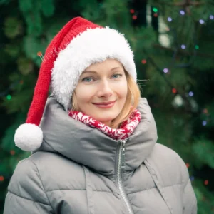 Santa Hat Knitting Pattern showing a long red knitted Santa hat with a soft fluffy white brim and a white pompom, an easy knit and purl Christmas hat for adults.
