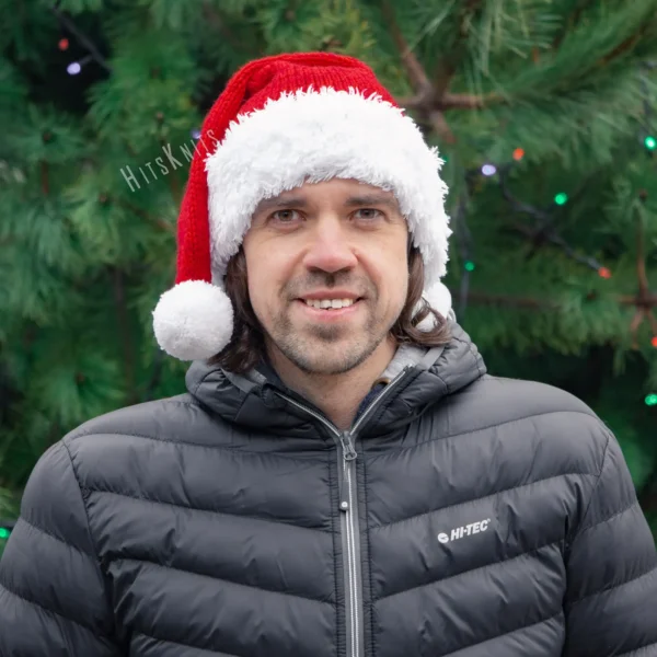 Santa Hat Knitting Pattern showing a long red knitted Santa hat with a soft fluffy white brim and a white pompom, an easy knit and purl Christmas hat for adults.