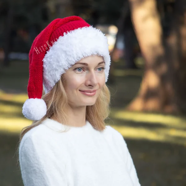 Santa Hat Knitting Pattern showing a long red knitted Santa hat with a soft fluffy white brim and a white pompom, an easy knit and purl Christmas hat for adults.