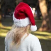Santa Hat Knitting Pattern showing a long red knitted Santa hat with a soft fluffy white brim and a white pompom, an easy knit and purl Christmas hat for adults.