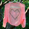 Lace Heart Bolero Knitting Pattern showing a lightweight pink lace shrug with an eyelet heart motif on the back, worked in sport weight cotton, sizes XS to 4XL.