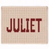 Juliet Chunky Blanket Knitting Pattern showing the name Juliet in deep red block letters running along the length of a soft cream blanket, worked in stockinette colorwork intarsia with 2 colors: Cream and Red.