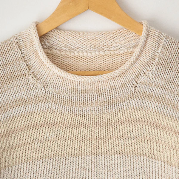 Cozy Women's Basic Sweater Knitting Pattern showing a relaxed drop-shoulder pullover in marled cream, oat, and sand, worked in stockinette stitch with rolled hem, cuffs, and neckline, sizes S to 2XL.