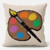 Artist Palette Knit Pillow Panel Pattern - a brown artist's paint palette with six colorful paint blobs and a paintbrush on a cream background, worked in stockinette colorwork intarsia with 10 colors.