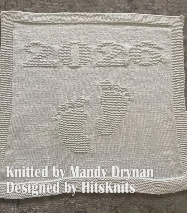 Minimalist knitted baby blanket with “2025” and baby feet motif in textured garter stitch on a smooth stockinette background, finished with a wide garter stitch border. Neutral blue newborn blanket design for stroller, nursery, baby shower gift, or pregnancy announcement photo prop.