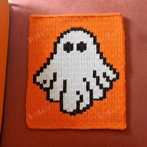 Halloween Ghost Finger Knit Blanket Pattern - a friendly white ghost with two dark eyes and a wavy hem on a bright orange background, knitted in stockinette colorwork intarsia with 3 colors: White, Orange, Black.