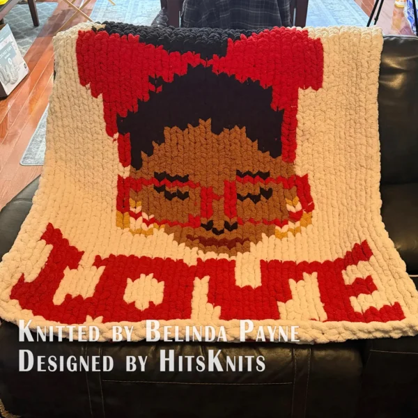 Love Yourself Finger Knit Blanket Pattern - motivational self-love portrait of an African American Black woman with an afro bun, a royal blue headband with a bow, blue glasses, gold hoop earrings and burgundy lips, above the word LOVE with floating hearts on a white background, knitted in stockinette colorwork intarsia with 8 colors: White, Royal Blue, Cornflower, Brown, Camel, Black, Gold, Burgundy.
