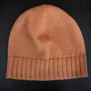Machine Knitting Slouchy Hat Pattern showing a warm brown cotton beanie with a deep mock rib cuff, worn slouchy, knitted on a standard gauge machine, adult size 56-58 cm.