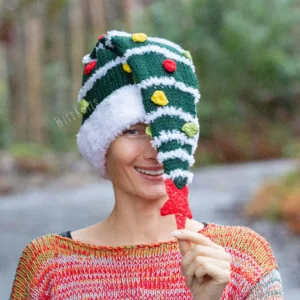 Christmas Tree Hat Knitting Pattern showing a tall dark green knitted beanie with a white fluffy Santa style brim and stripes, yellow, red and green bobbles and a red crochet star on top, knitted flat and seamed, worked in bulky yarn, unisex adult size 56-59 cm.