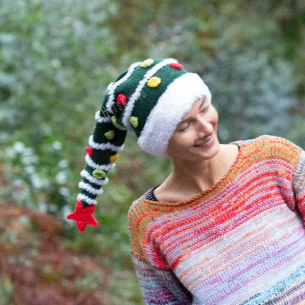 Christmas Tree Hat Knitting Pattern showing a tall dark green knitted beanie with a white fluffy Santa style brim and stripes, yellow, red and green bobbles and a red crochet star on top, knitted flat and seamed, worked in bulky yarn, unisex adult size 56-59 cm.